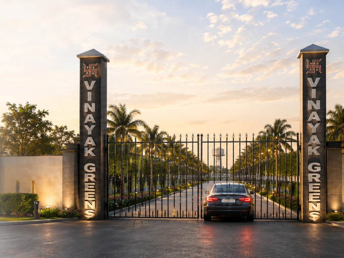 Tall stone pillars and palm-lined driveway at the Vinayak Greens gate